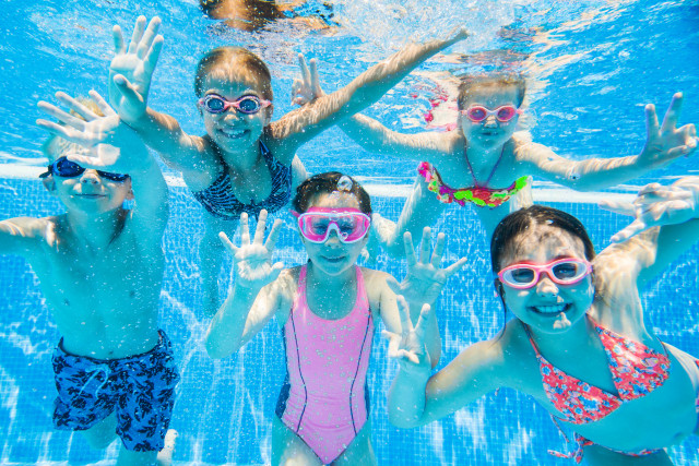 little kids swimming  in pool  underwater.